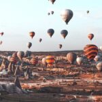 Hot air balloons over rocky terrain with a black-and-white ladybug costume drawing in the corner