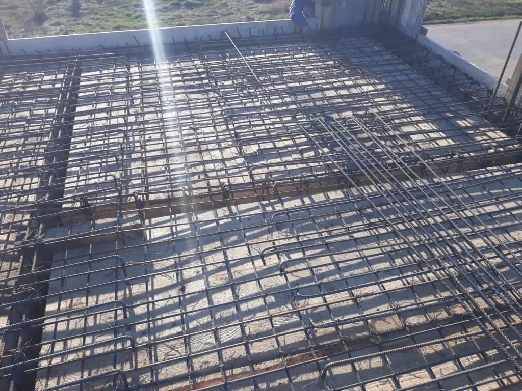 Concrete slab framework with steel rebar grid and wooden formwork at a construction site.